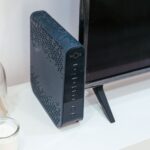 Nowoczesny salon z routerem Wi‑Fi, telewizorem i szklaną dekoracją