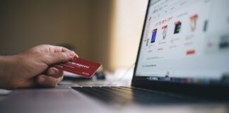 Osoba wpisująca dane karty przy zakupach online na laptopie