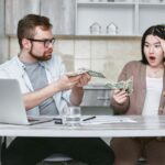 Zszokowana para przy stole liczy gotówkę i martwi się wydatkami