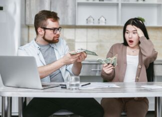 Zszokowana para przy stole liczy gotówkę i martwi się wydatkami