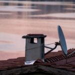 Antena satelitarna i komin na dachu o świcie