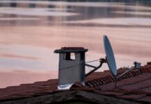 Porównanie ofert internetu satelitarnego w Polsce koszty, limity, prędkości i ukryte opłaty Antena satelitarna i komin na dachu o świcie