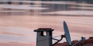 Antena satelitarna i komin na dachu o świcie