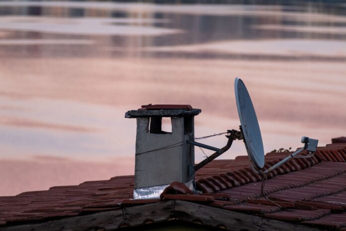 Antena satelitarna i komin na dachu o świcie