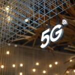 Podświetlony napis 5G na tle nowoczesnego, geometrycznego sufitu