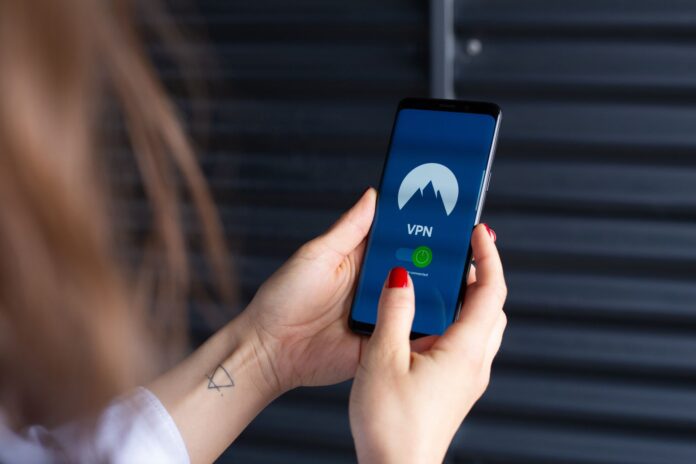 Kobiece dłonie uruchamiają aplikację VPN na smartfonie Kobiece dłonie uruchamiają aplikację VPN na smartfonie