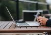 Mężczyzna korzysta z internetu w telefonie przy laptopie w kawiarni