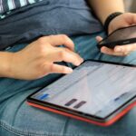Osoba korzysta równocześnie ze smartfona i tabletu w podróży