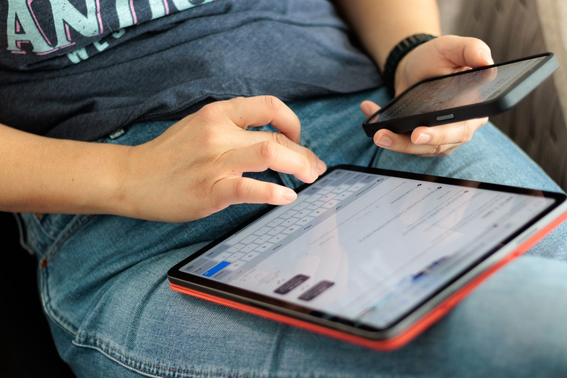 Osoba korzysta równocześnie ze smartfona i tabletu w podróży