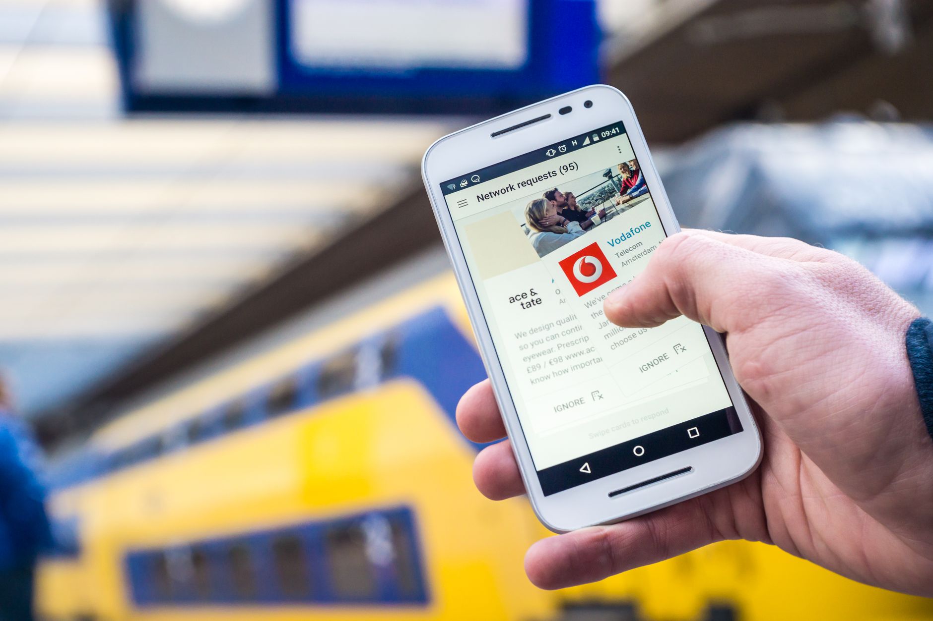 Osoba korzysta ze smartfona na peronie z przejeżdżającym pociągiem