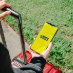 Osoba z walizką sprawdza aplikację eSIM na smartfonie na ulicy